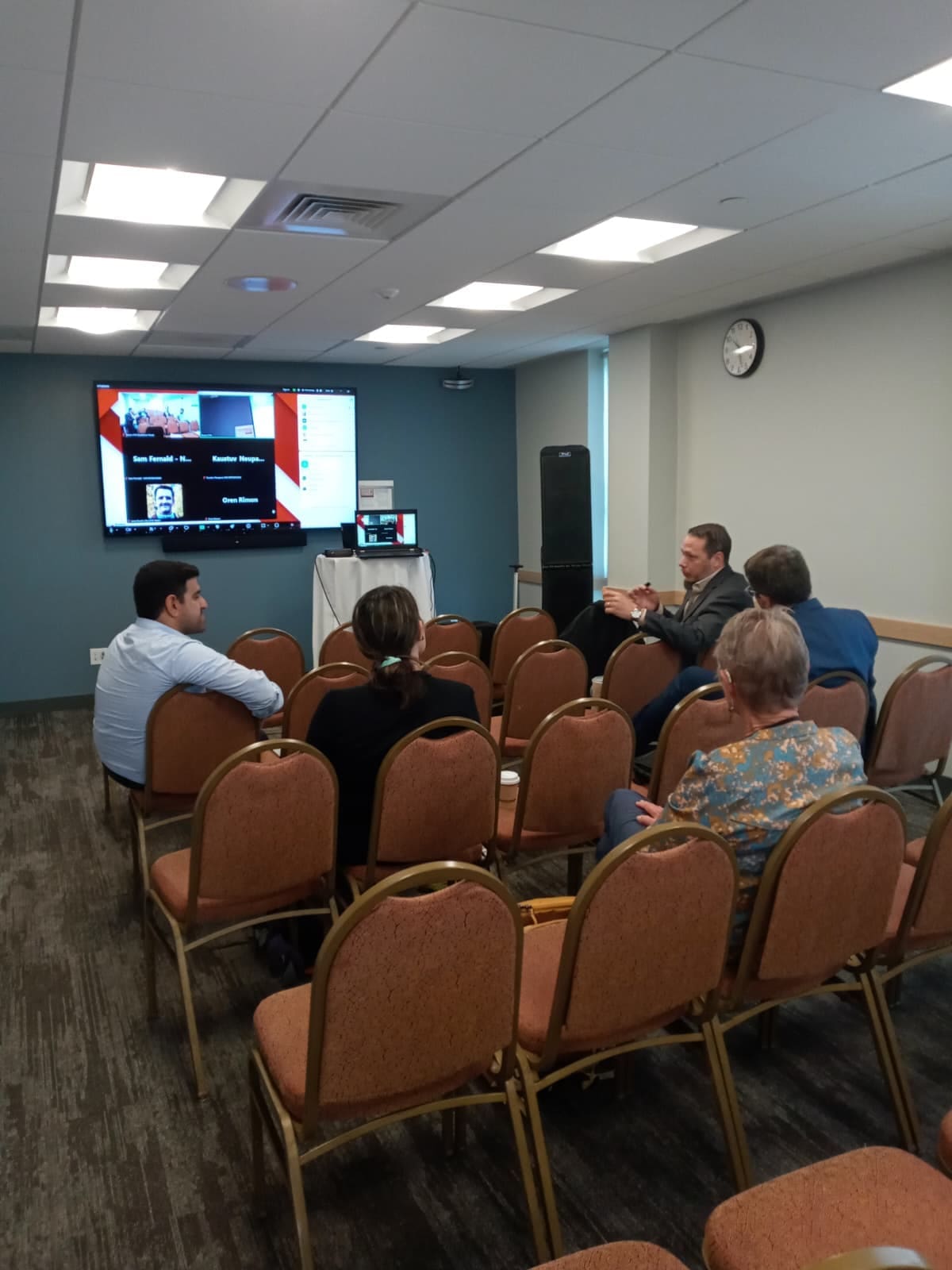 Image of a physical and Zoom room of men and women interested in water and system dynamics